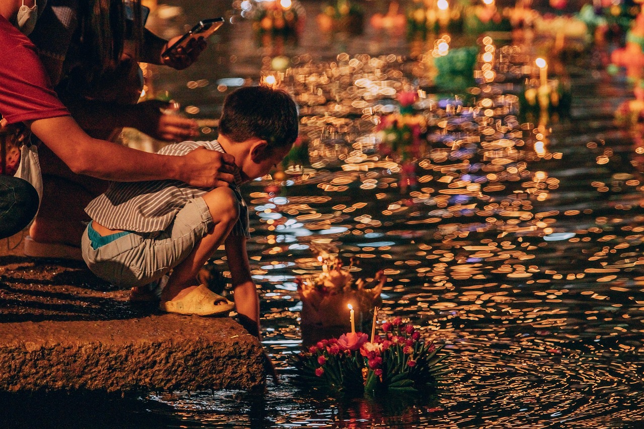EIn Kind lässt sein Loy Kratong Boot ins Wasser